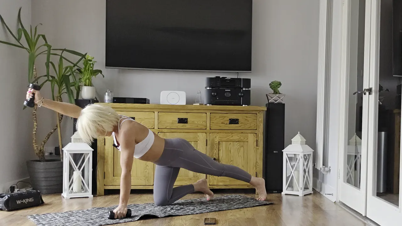 Anna doing a bird dog on a mat in her living room