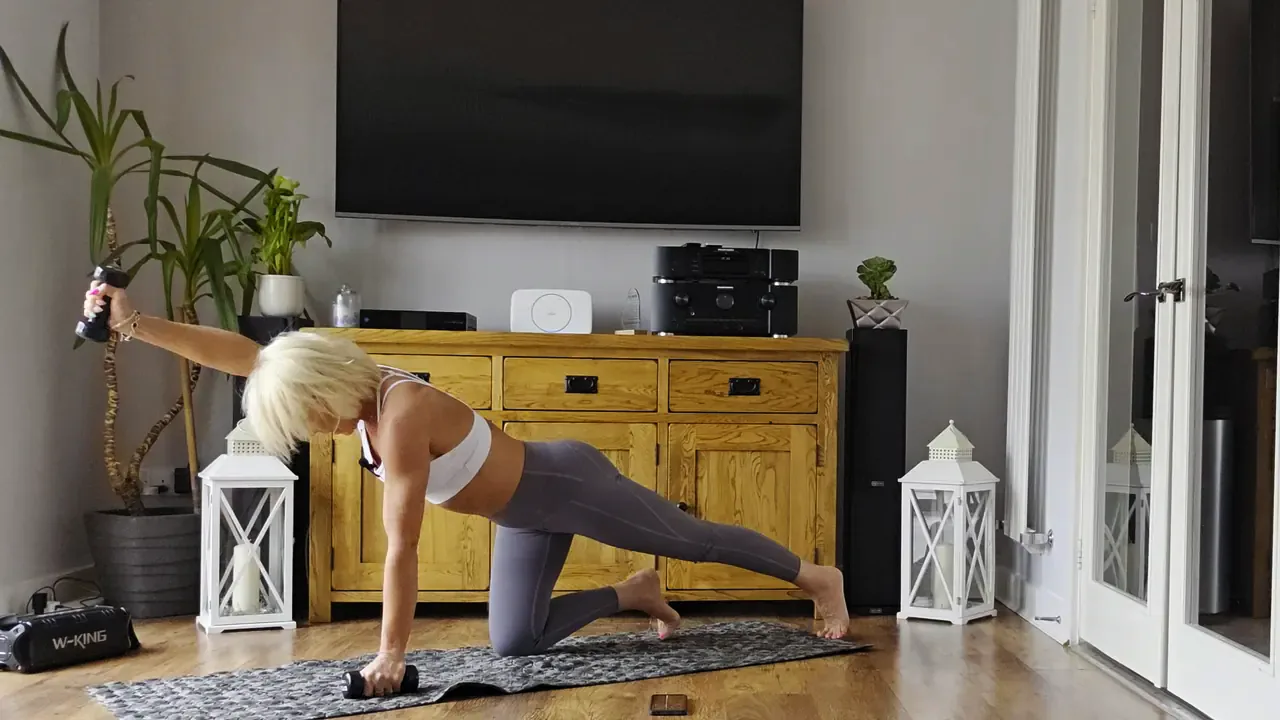 Anna doing a bird dog on a mat in her living room